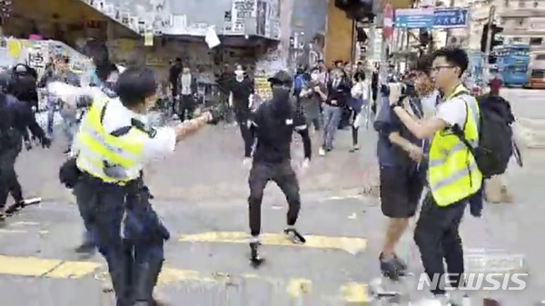 11일(현지시간) 온라인에 유포된 동영상 속에서 한 홍콩 경찰관이 시위 현장에서 다가오는 시위자를 향해 총을 겨누고 있다.  [사진=뉴시스]