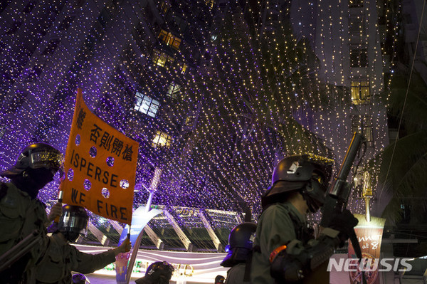 1일(현지시간) 홍콩 시민들이 거리로 나와 시위를 벌인 가운데 홍콩 경찰이 이들을 향해 해산하라는 팻말을 들어 보이고 있다. 이날 시위에는 검은 옷과 마스크 차림의 청년뿐 아니라 아이들을 대동한 부모들도 상당수 함께했다. [사진=뉴시스]