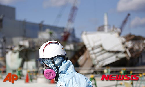 작업복으로 무장한 한 작업원이 지난 2월10일 일본 후쿠시마(福島)현 오쿠마정(大熊町)에 위치한 후쿠시마 제1원전에서 동일본대지진으로 멜트다운 된 원자로 1호기 앞을 지나가고 있다. [사진=뉴시스]