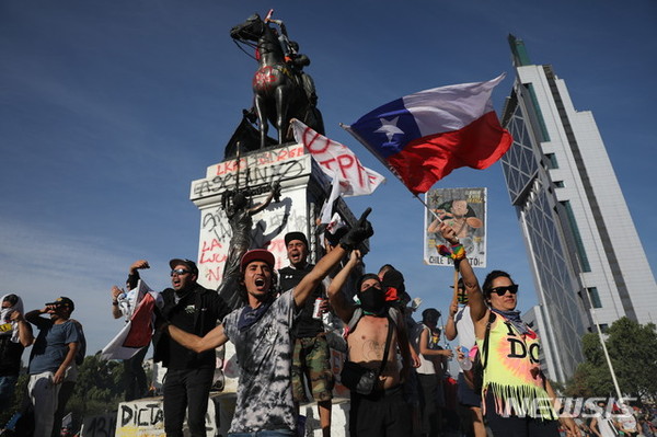 30일(현지시간) 칠레 수도 산티아고에서 반정부시위대가 구호를 외치며 시위하고 있다. 세바스티안 피녜라 칠레 대통령은 이날 시위로 인한 내부 혼란으로 11월 APEC과 12월 기후변화협약 당사국 총회(COP) 개최를 취소한다고 밝혔다. [사진=뉴시스]