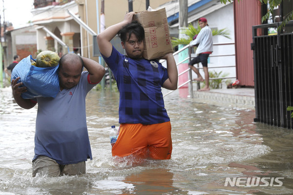 [ 인도네시아 자카르타 인근에 지난달 31일(현지시간)부터 1일 새벽까지 내린 폭우로 홍수가 발생한 가운데 2일 자카르타 외곽 탕게랑 마을 주민들이 침수된 도로를 힘겹게 건너고 있다 / 사진 = 뉴시스 ]
