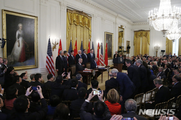 15일(현지시간) 미국 워싱턴 백악관에서 류허 중국 부총리(왼쪽)과 도널드 트럼프 미국 대통령(오른쪽)이 앉아 1단계 미중 무역합의문에 서명하고 있다. [사진=뉴시스]