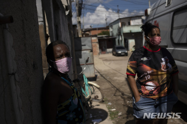 [ 19일(현지시간) 브라질 리우데자네이루의 빈민가에서 의료진이 신종 코로나바이러스 감염증(코로나19) 증세로 의심되는 한 남성을 살피는 동안 가족들이 밖에서 대기하고 있다 / 사진 = 뉴시스 ]
