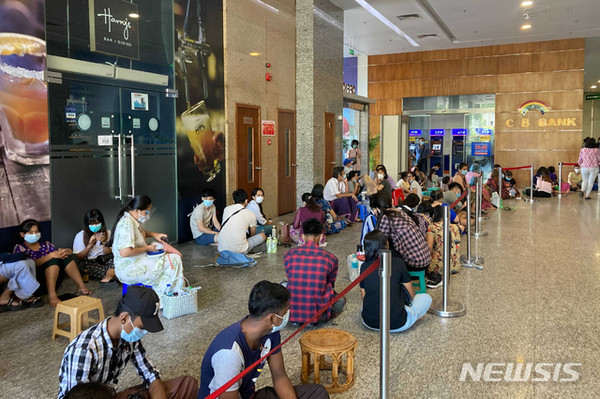 미얀마 양곤 시내 한 은행 지점 현금자동인출기(ATM)에서 현금을 인출하려는 시민들이 바닥에 앉아 몇 시간째 기다리고 있다/ 사진= 뉴시스 제공.