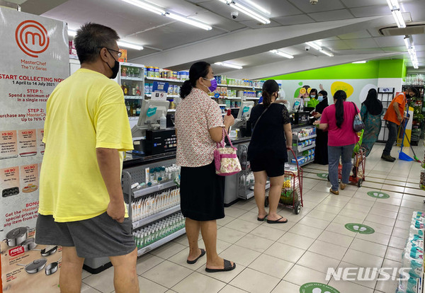 싱가포르의 한 슈퍼마켓에서 코로나19 확산 방지를 위해 마스크를 쓴 사람들이 사회적 거리를 두고 계산을 하기 위해 줄 서 있다./사진=뉴시스 제공.