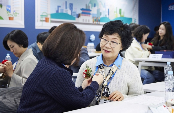 SBI저축은행이 진행한 가족 초청 행사 ‘부모님 오신데이(Day)’에서 직원들이 부모님께 카네이션을 달아드리고 있다.／사진=SBI저축은행 제공